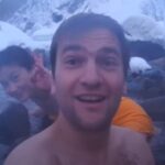 海外の方と日本人の男女のグループが雪の降る中混浴露天風呂を楽しむ様子【切明温泉】